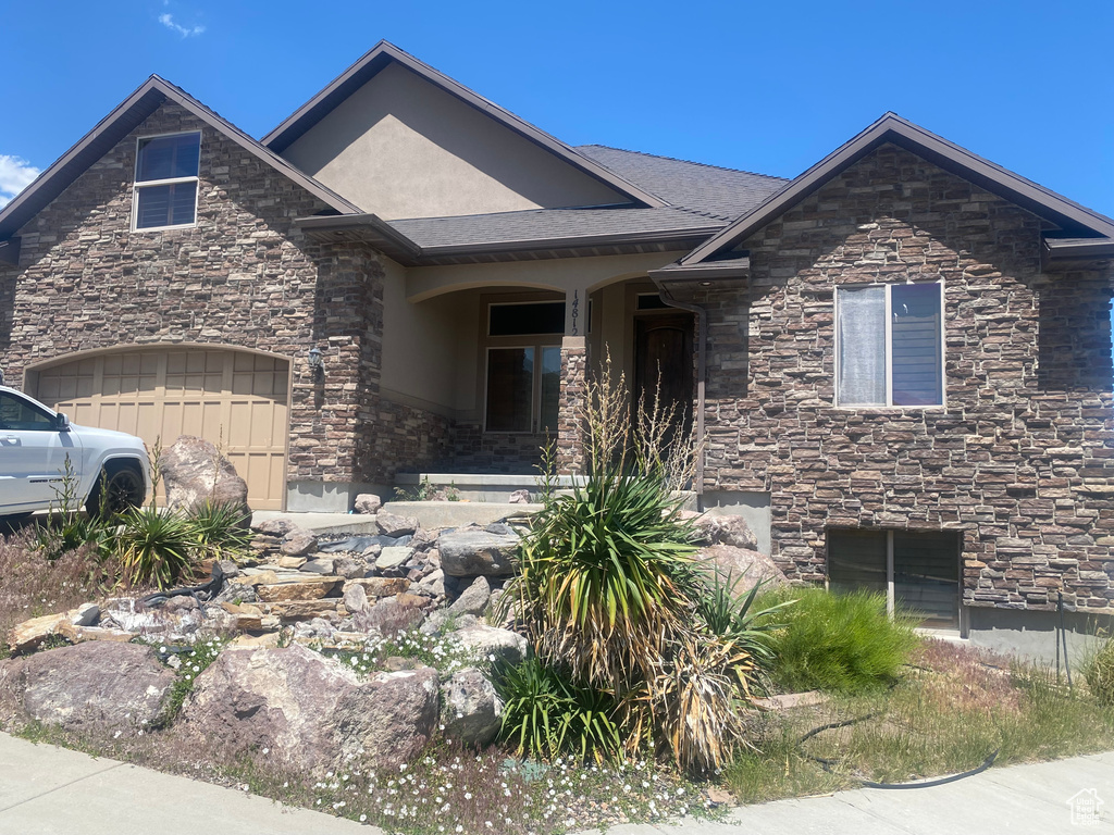 View of front of home with stone siding, stucco siding, and a garage