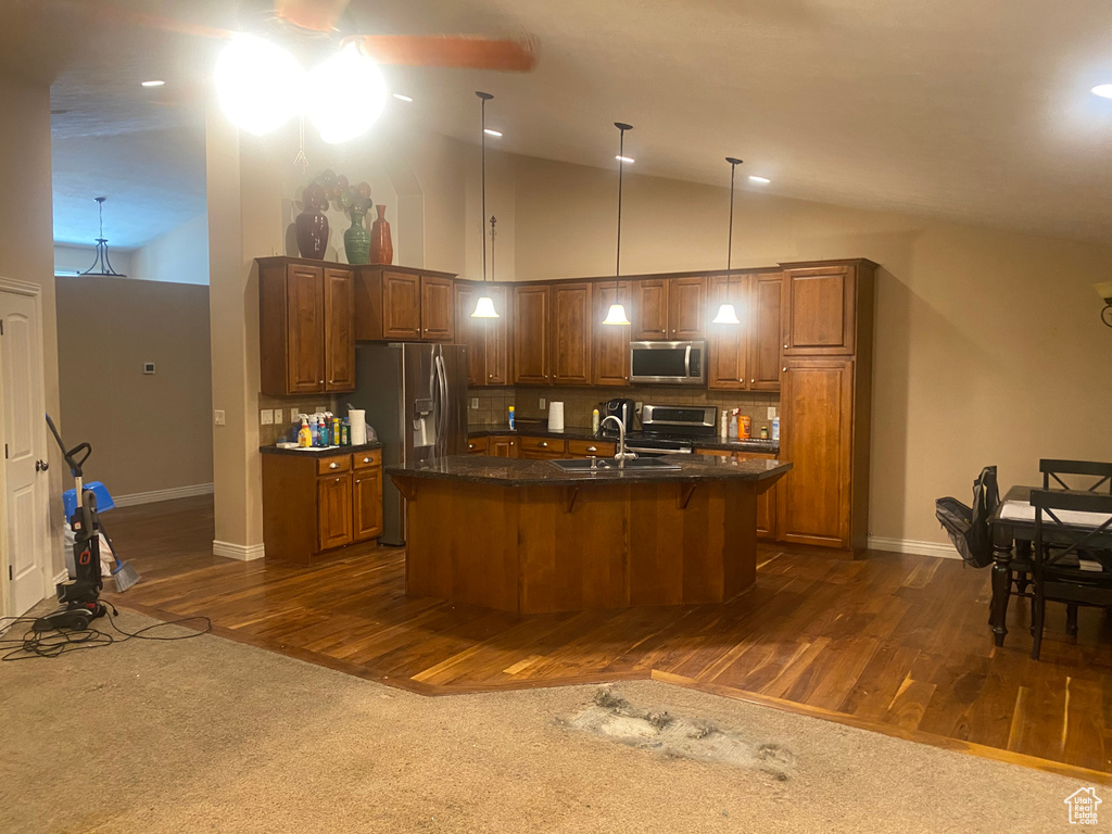Kitchen featuring appliances with stainless steel finishes, backsplash, dark wood-style flooring, a kitchen breakfast bar, and vaulted ceiling