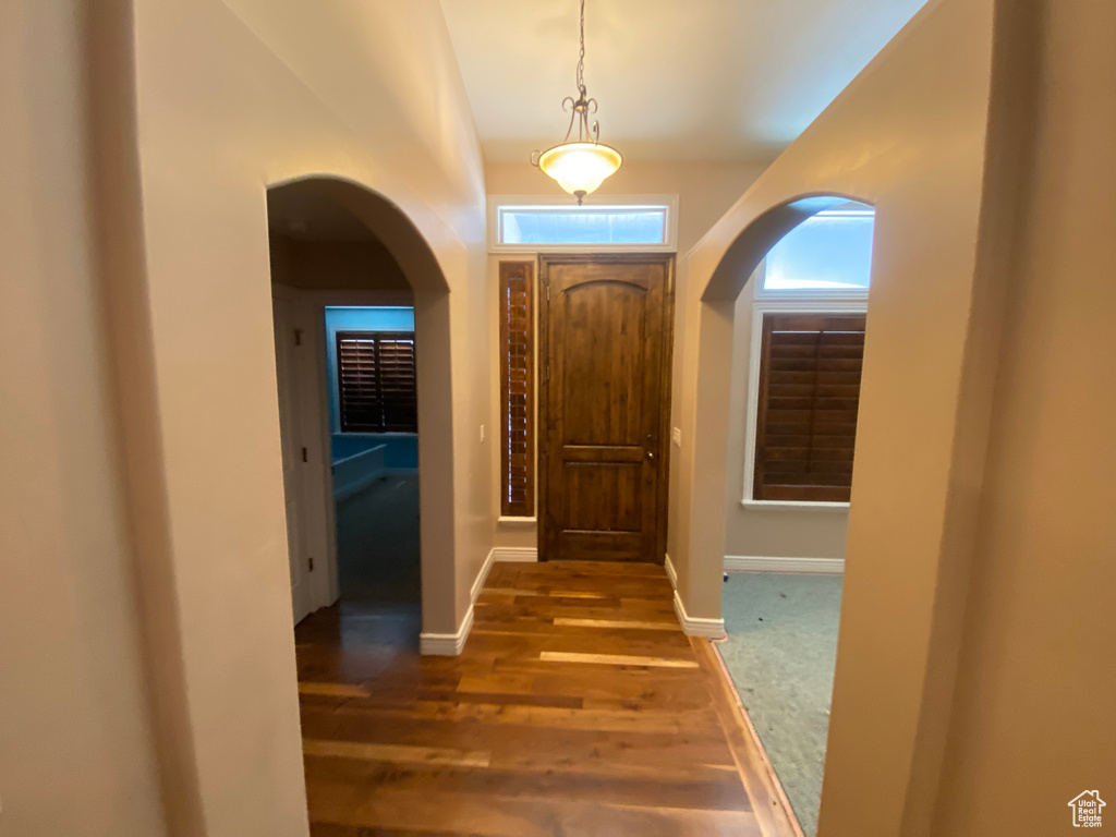 Foyer with arched walkways and wood finished floors
