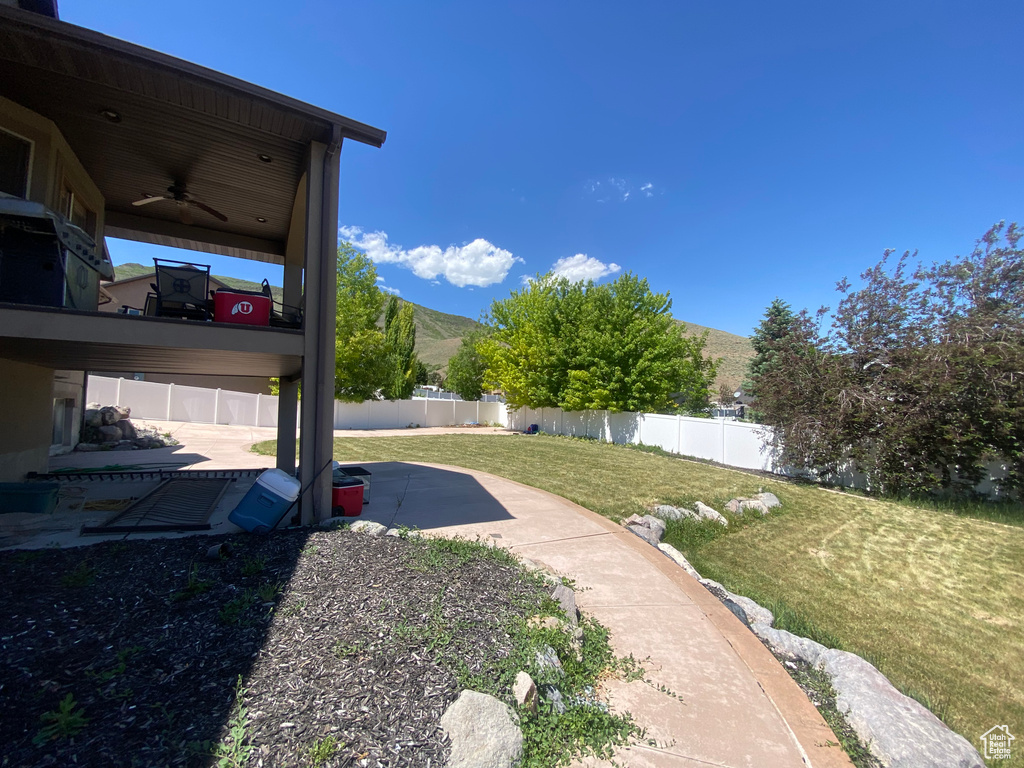 Fenced backyard with a ceiling fan, a mountain view, and a patio