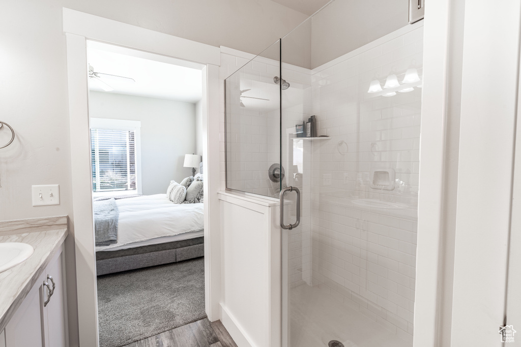 Bathroom featuring vanity, connected bathroom, a shower stall, and wood finished floors
