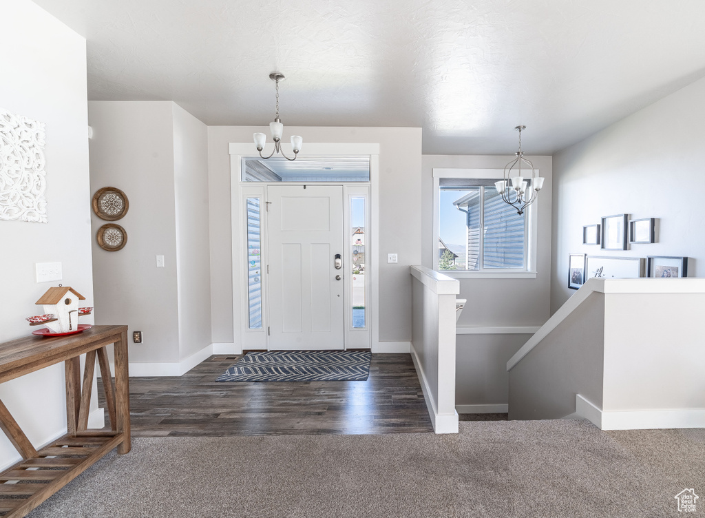 Carpeted entrance foyer featuring a chandelier and wood finished floors