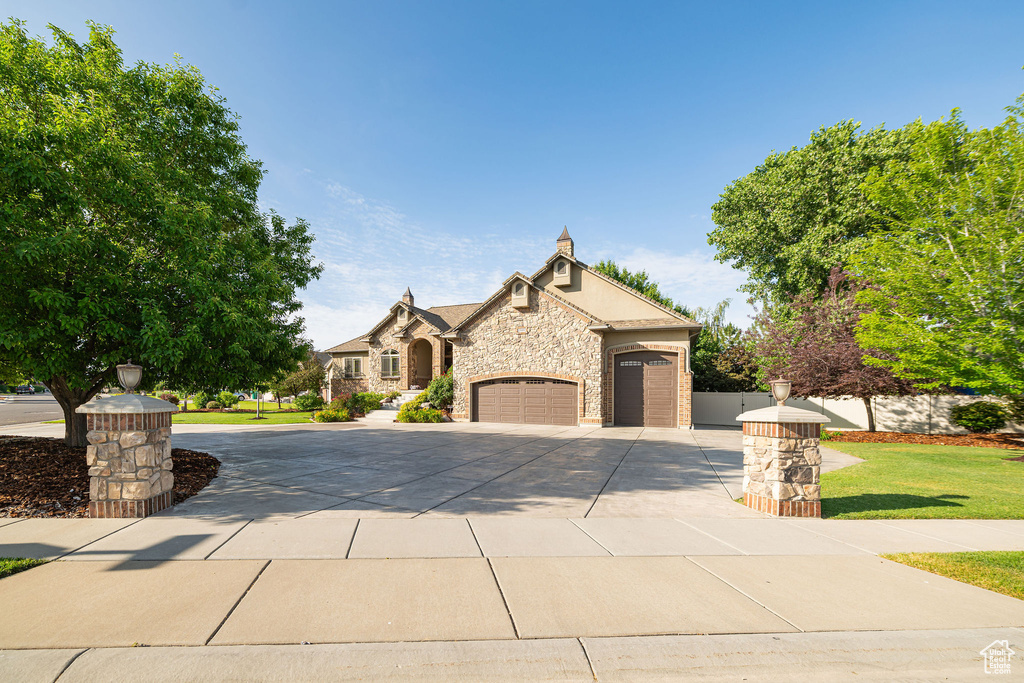 View of front of home featuring driveway, an attached garage, and stone siding