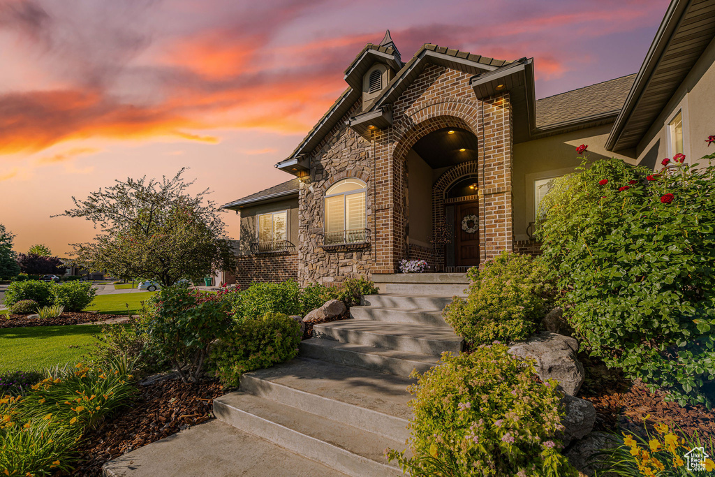 View of front facade with brick siding, stucco siding, and covered porch