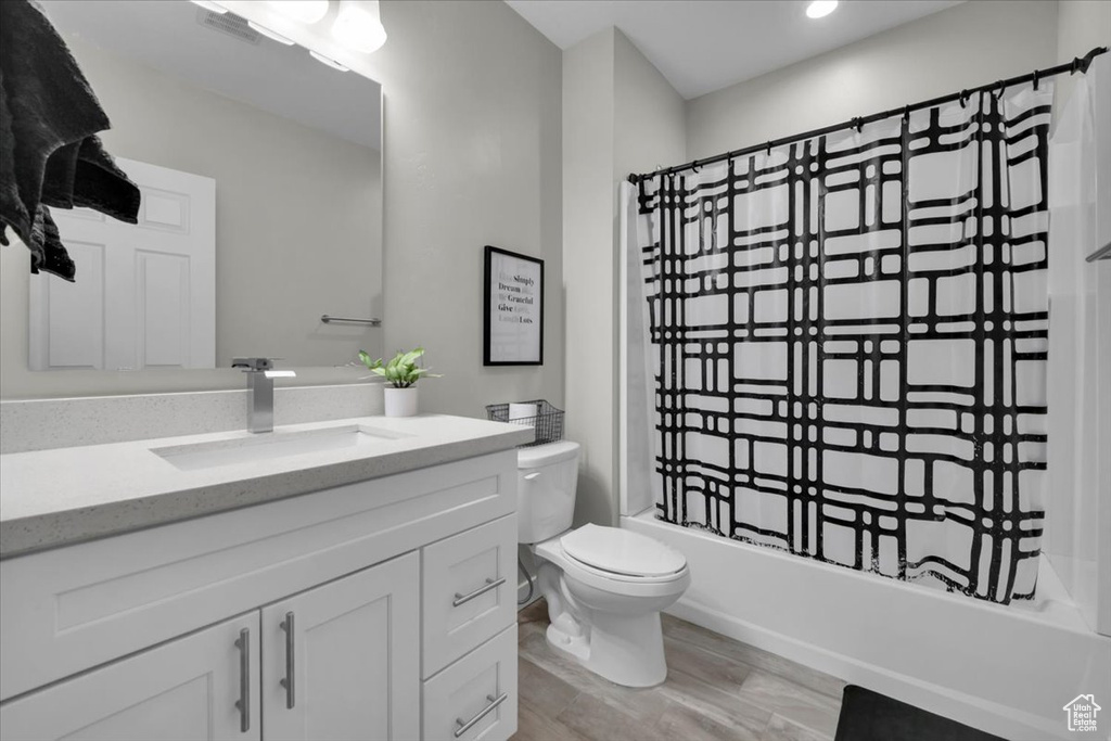 Bathroom featuring vanity, shower / tub combo with curtain, wood finished floors, and recessed lighting