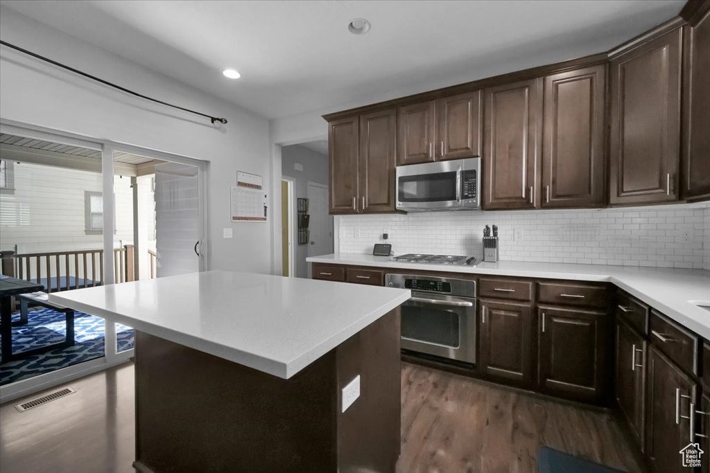 Kitchen with appliances with stainless steel finishes, dark wood-style floors, light countertops, dark brown cabinetry, and recessed lighting