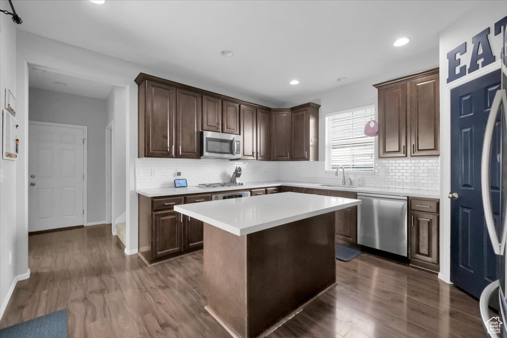Kitchen with appliances with stainless steel finishes, light countertops, dark wood-style floors, tasteful backsplash, and recessed lighting