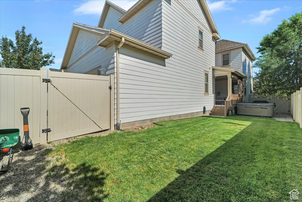 Fenced backyard featuring a gate and a hot tub
