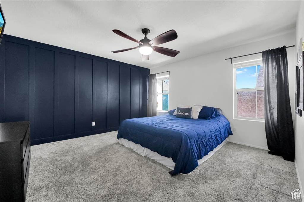 Carpeted bedroom with multiple windows and ceiling fan