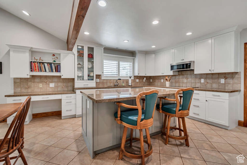 Kitchen with stainless steel microwave, light tile patterned floors, white cabinets, recessed lighting, and vaulted ceiling