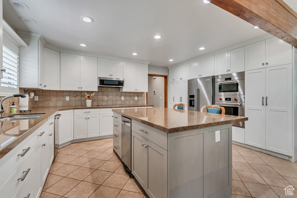 Kitchen featuring appliances with stainless steel finishes, light tile patterned flooring, decorative backsplash, a center island, and recessed lighting