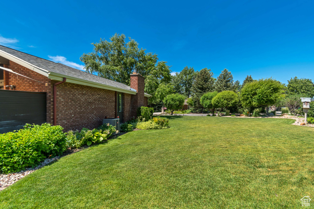 View of green lawn featuring an attached garage