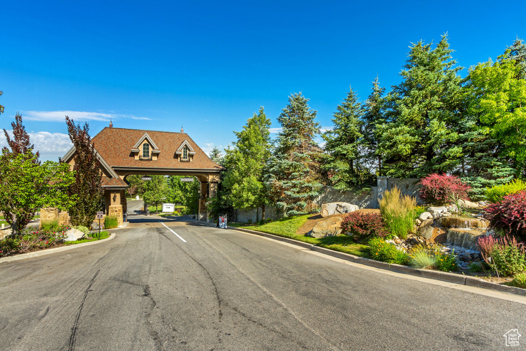 View of asphalt road featuring curbs and a gated entry