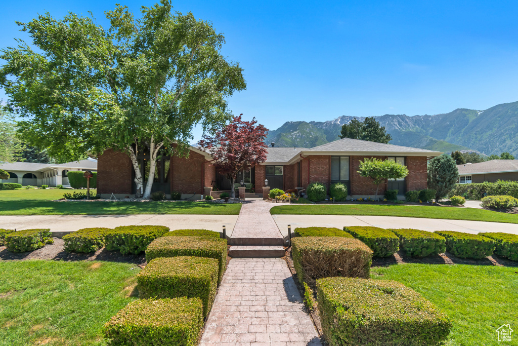 View of front facade with a mountain view, a front yard, and brick siding