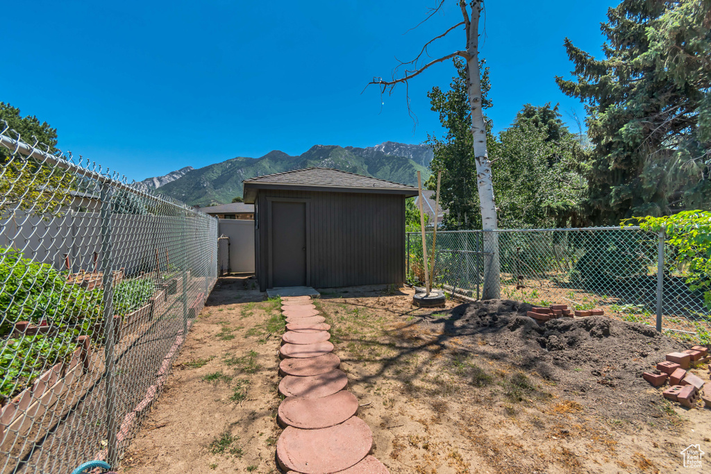 Fenced backyard featuring a mountain view, a storage unit, and a vegetable garden