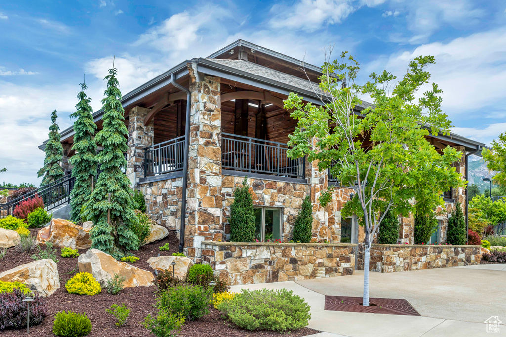 View of front of home with stone siding and a balcony