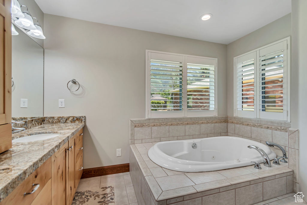 Bathroom featuring vanity, a jetted tub, tile patterned flooring, and recessed lighting