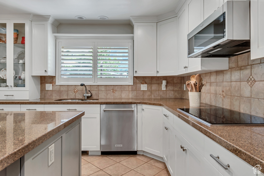 Kitchen featuring stainless steel appliances, white cabinets, and tasteful backsplash