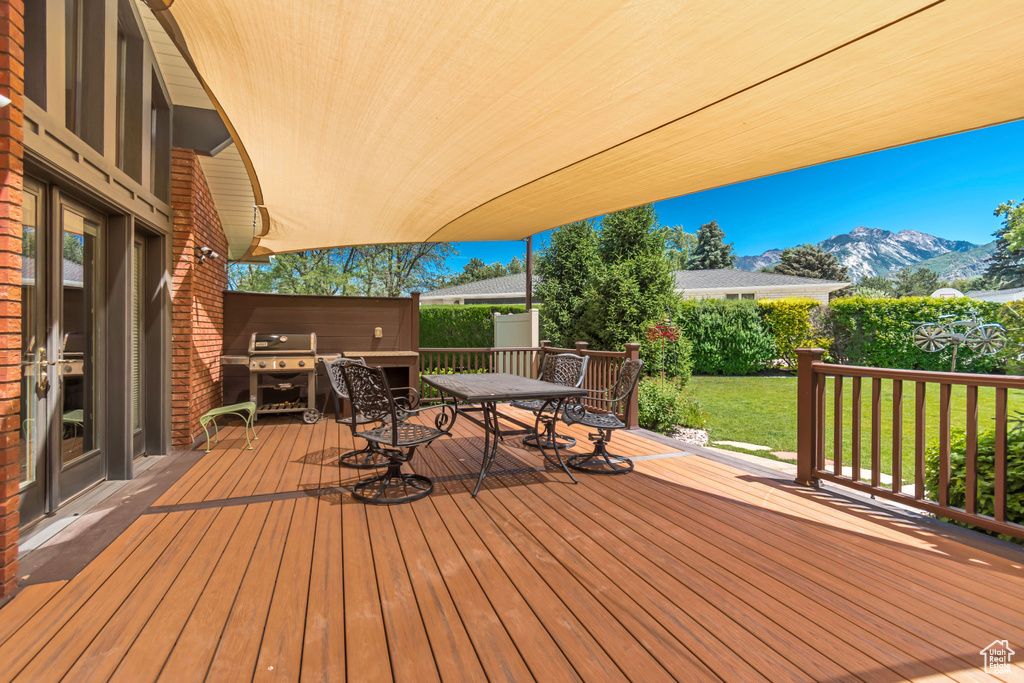 Deck featuring a grill, outdoor dining space, a mountain view, and a yard
