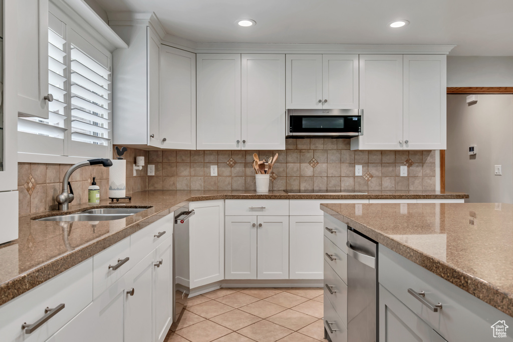 Kitchen with appliances with stainless steel finishes, backsplash, white cabinetry, light tile patterned flooring, and recessed lighting