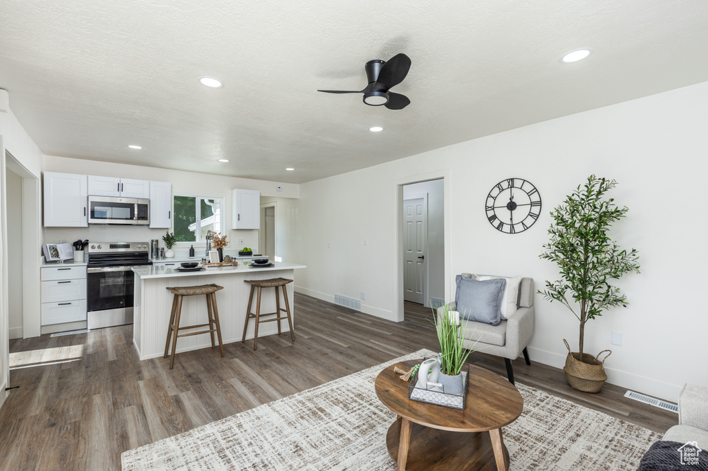 Living room with ceiling fan, dark wood-style flooring, and recessed lighting