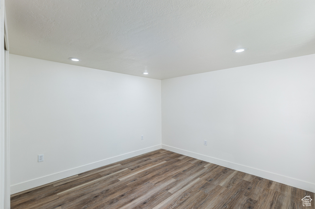Empty room with wood finished floors, recessed lighting, and a textured ceiling