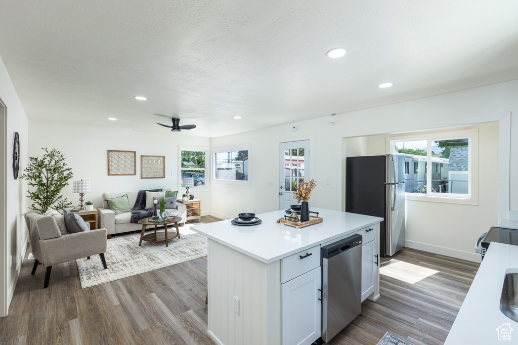 Kitchen featuring appliances with stainless steel finishes, light countertops, dark wood-style flooring, recessed lighting, and a center island
