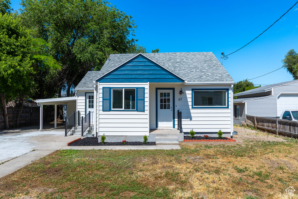 Bungalow-style house featuring a shingled roof, driveway, and an attached carport