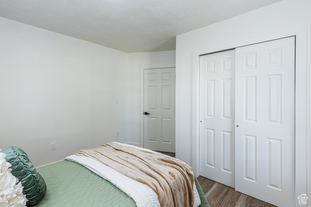 Bedroom with dark wood finished floors and a closet