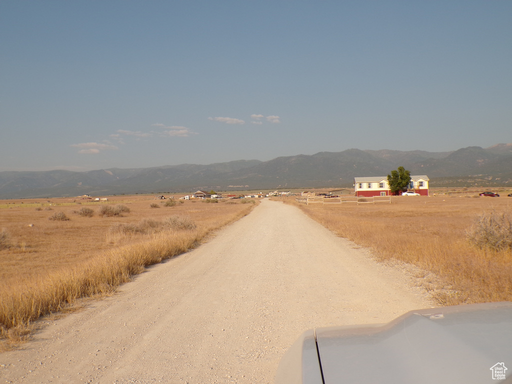 View of dirt / gravel road with a mountain view and a rural view