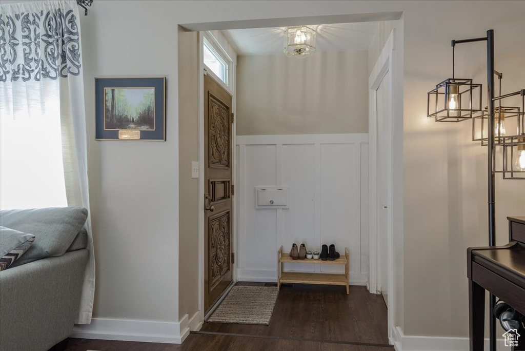 Entrance foyer featuring a decorative wall, dark wood-type flooring, wainscoting, and a chandelier