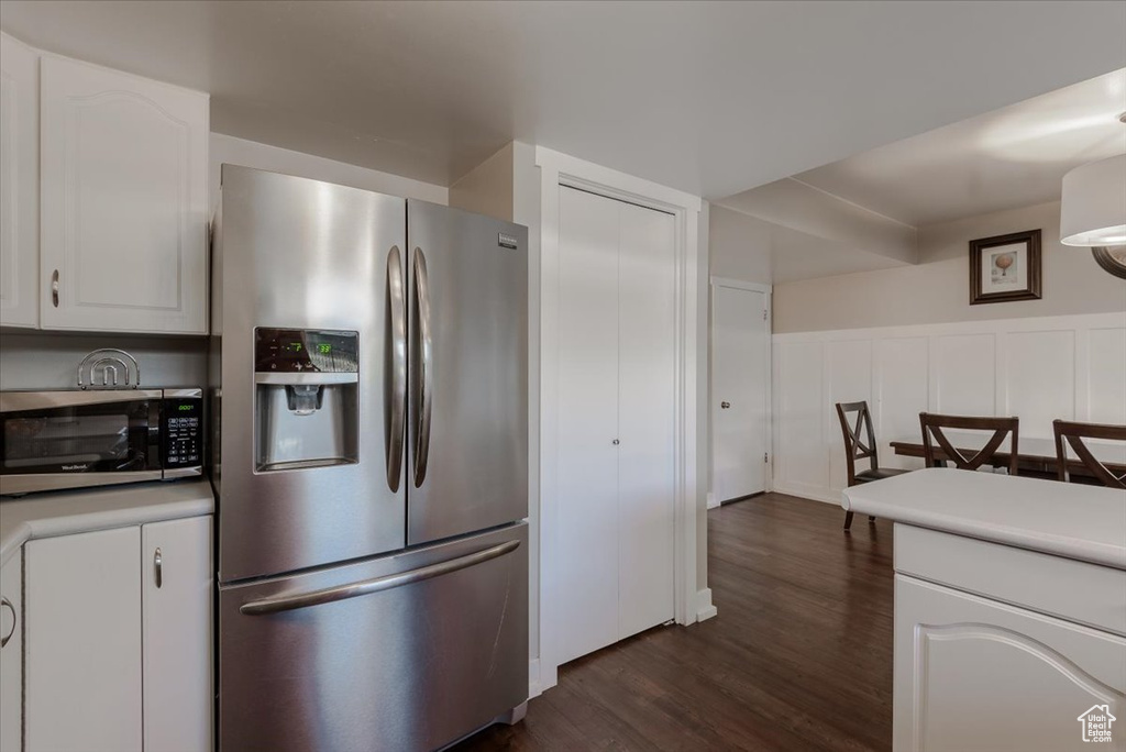 Kitchen featuring stainless steel appliances, dark wood-style flooring, white cabinets, and light countertops