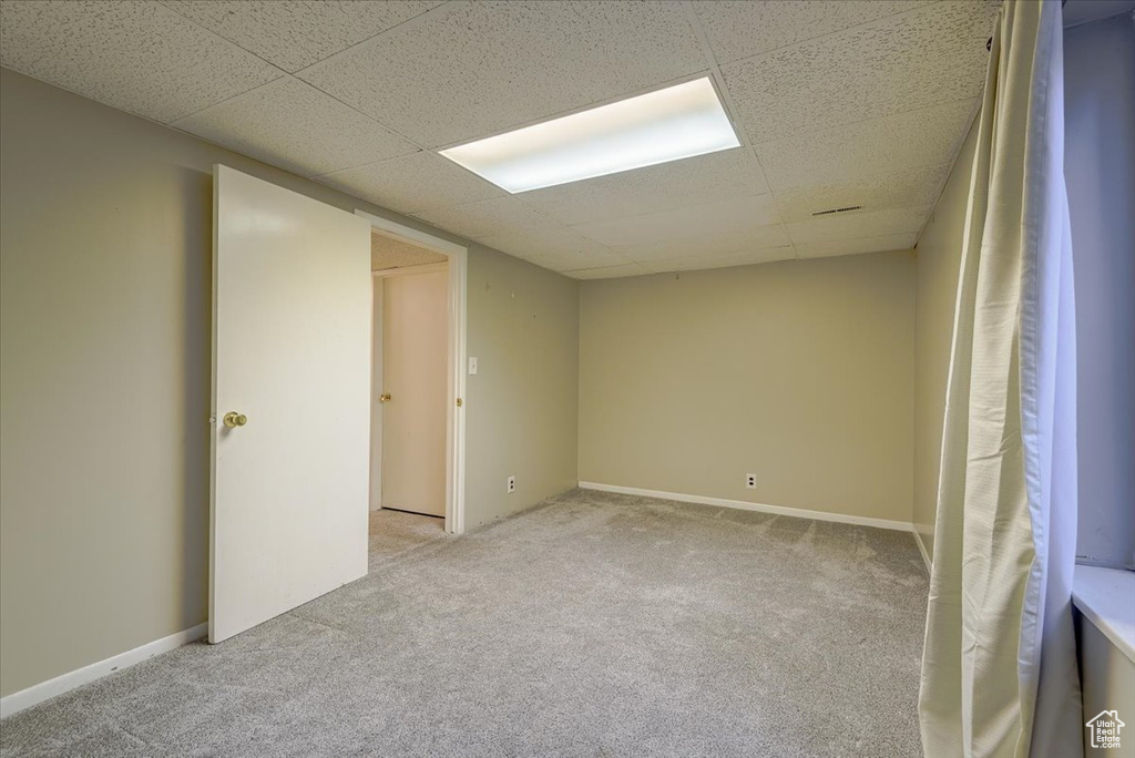 Carpeted empty room featuring a paneled ceiling and baseboards