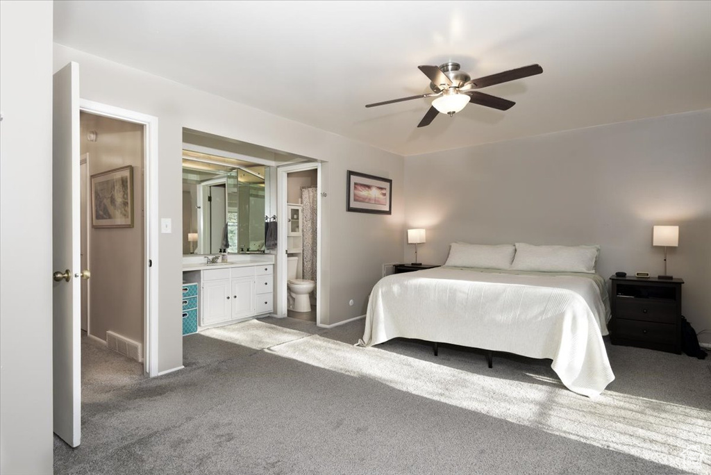 Bedroom with carpet floors, a sink, baseboards, and ensuite bathroom