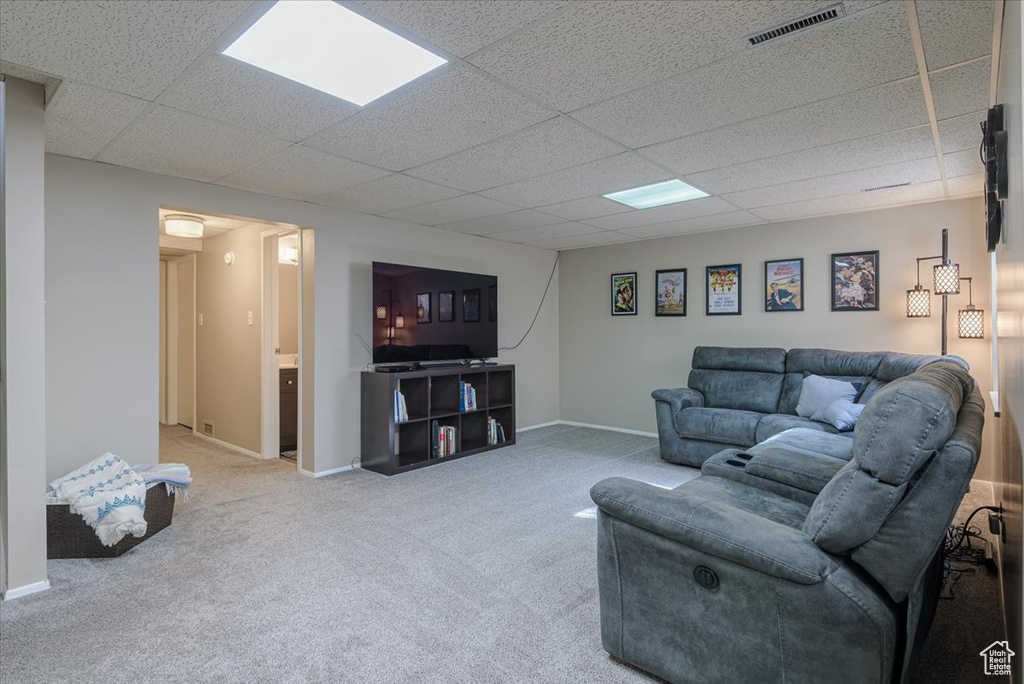 Carpeted living area with a drop ceiling and baseboards