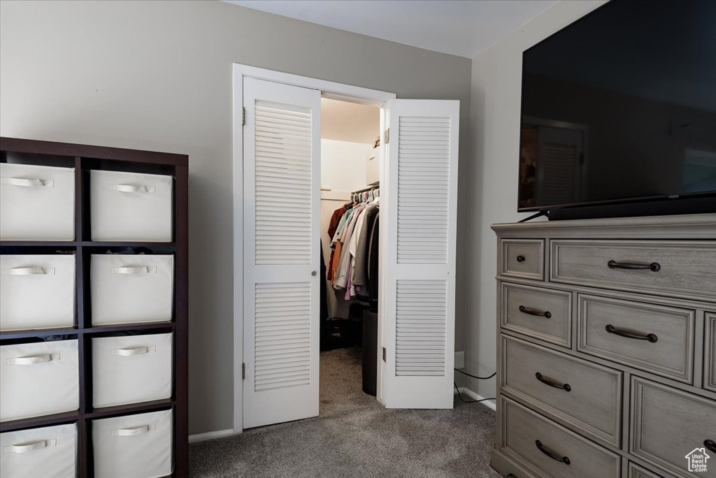 Bedroom with dark carpet, a walk in closet, and a closet
