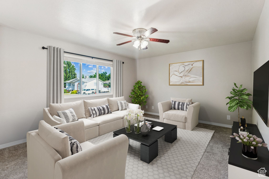 Carpeted living area with ceiling fan and baseboards