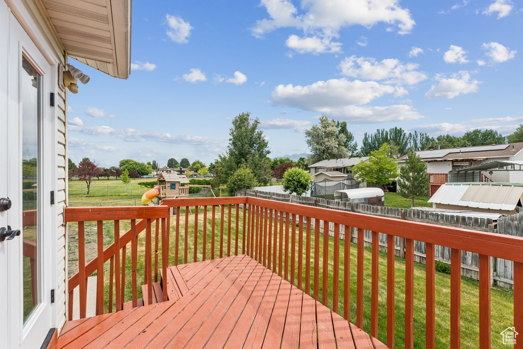 Wooden terrace with a fenced backyard, a playground, and a residential view