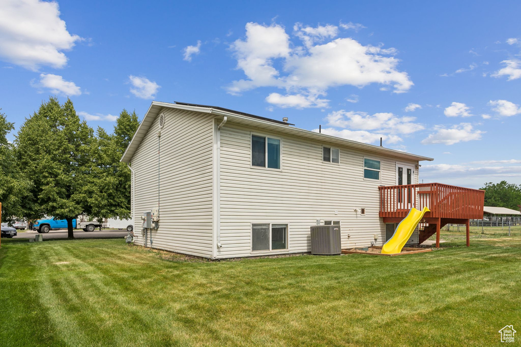 Rear view of house with a deck, a lawn, and stairs