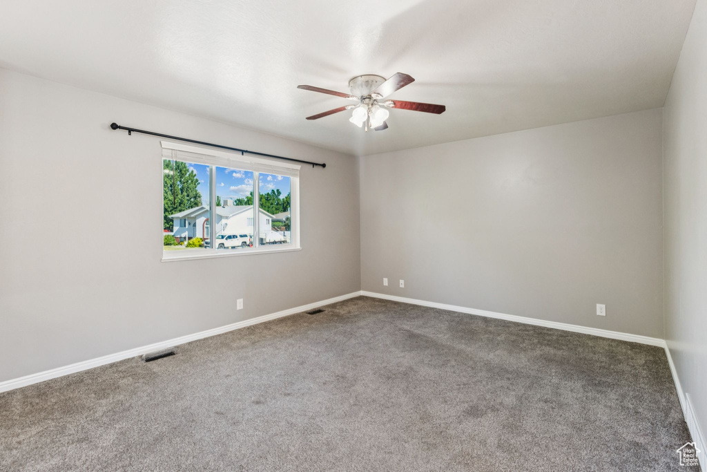 Carpeted spare room with a ceiling fan and baseboards