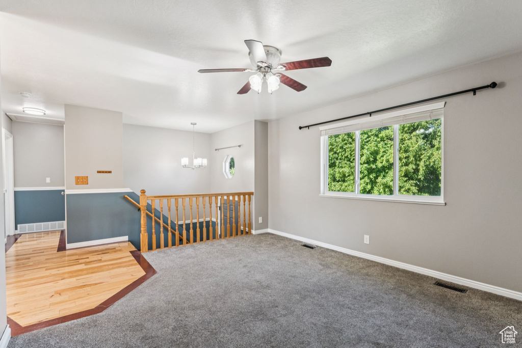 Unfurnished room with ceiling fan, a chandelier, and carpet flooring