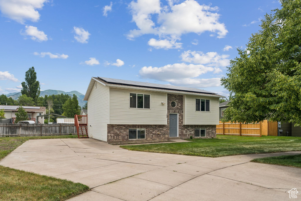 Raised ranch with roof mounted solar panels, a mountain view, and brick siding