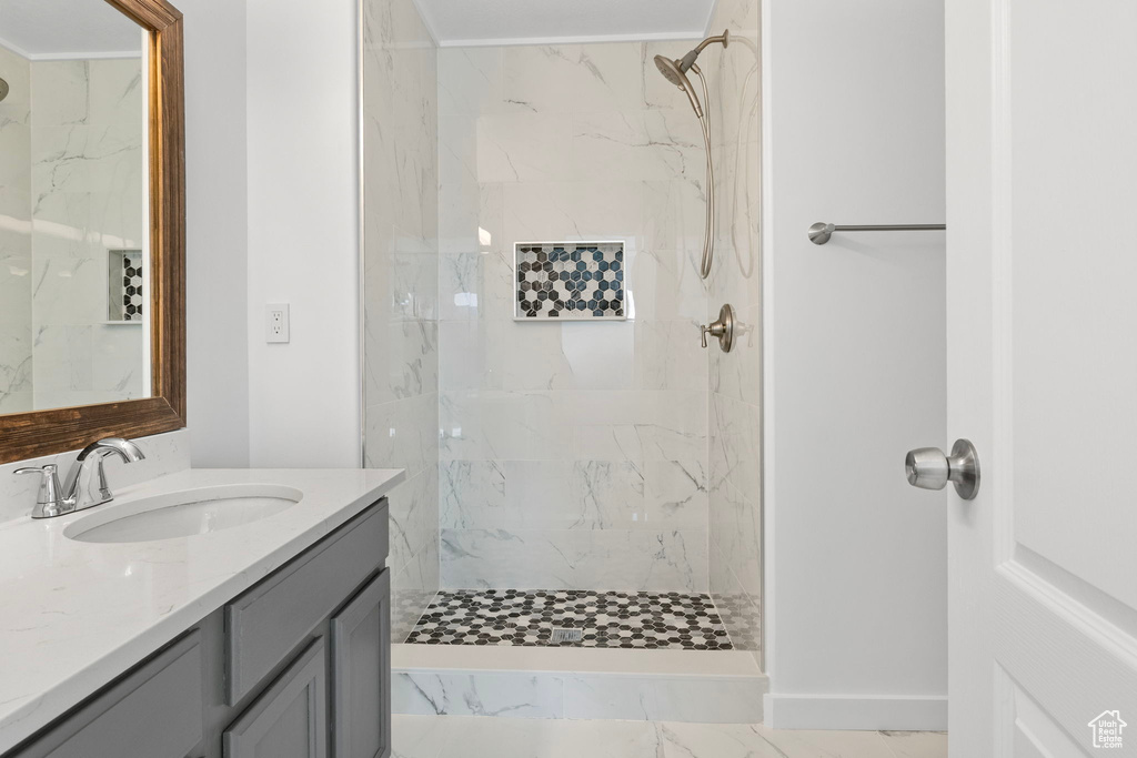 Full bath featuring vanity and a marble finish shower