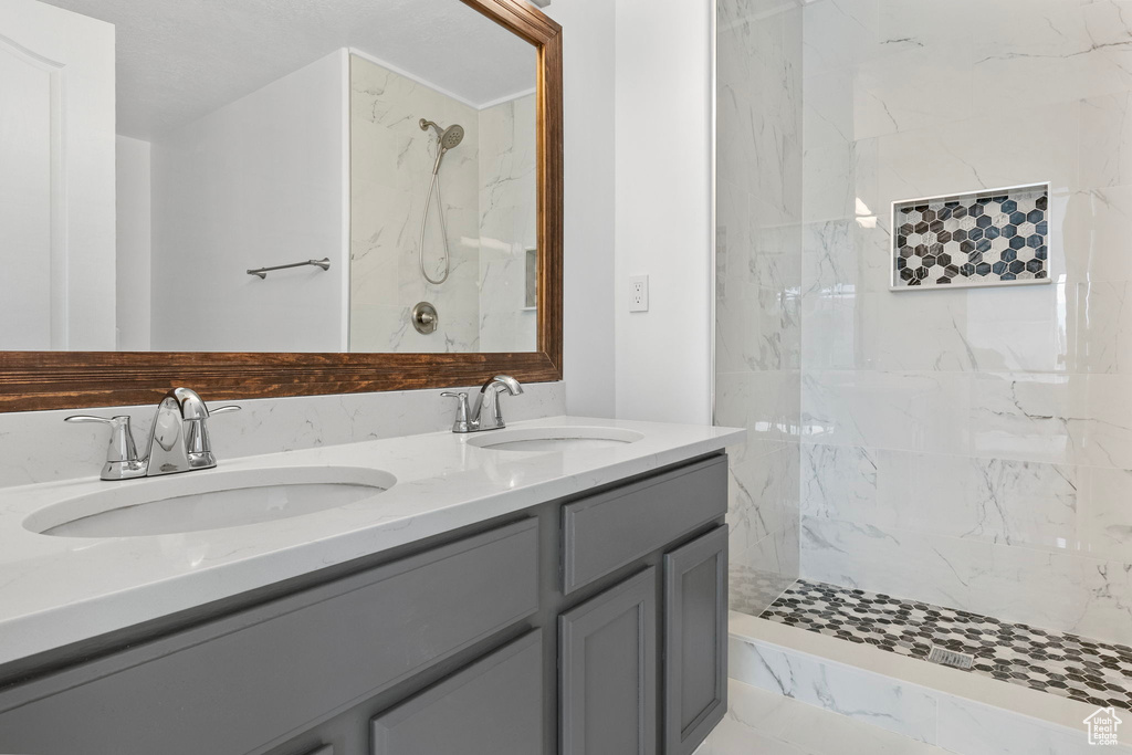 Bathroom with double vanity and a marble finish shower