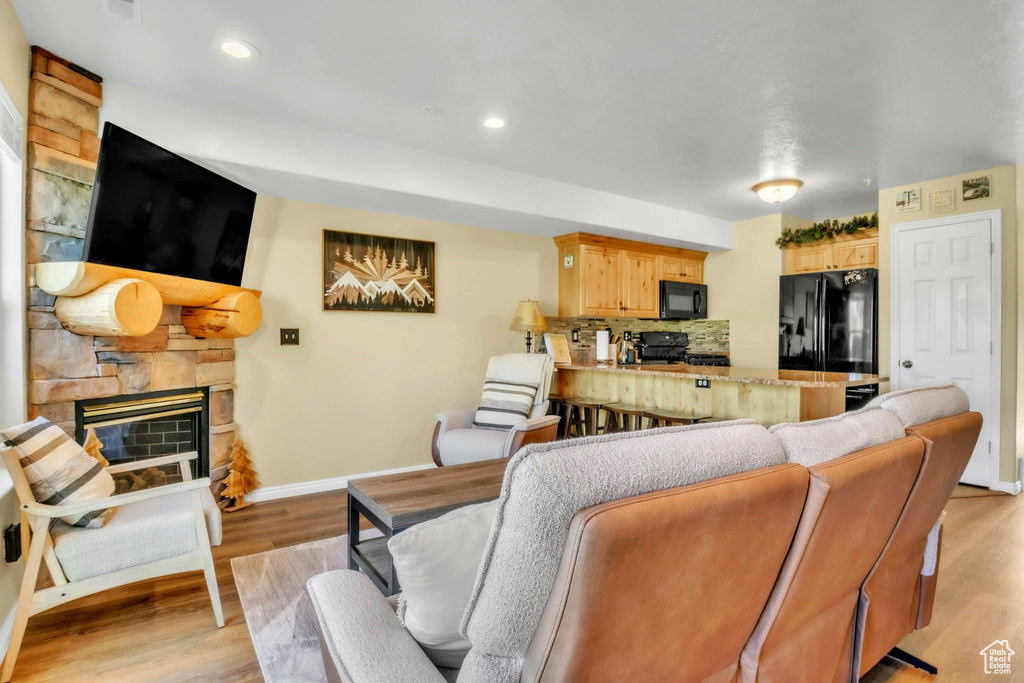 Living area with a fireplace, light wood-style floors, and recessed lighting