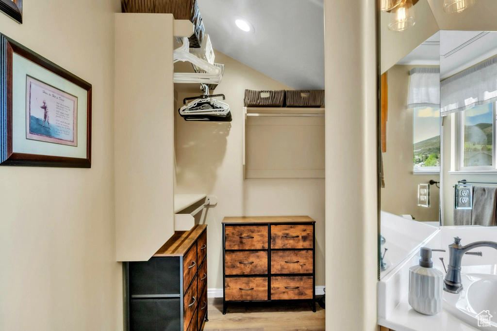 Walk in closet with wood finished floors and vaulted ceiling