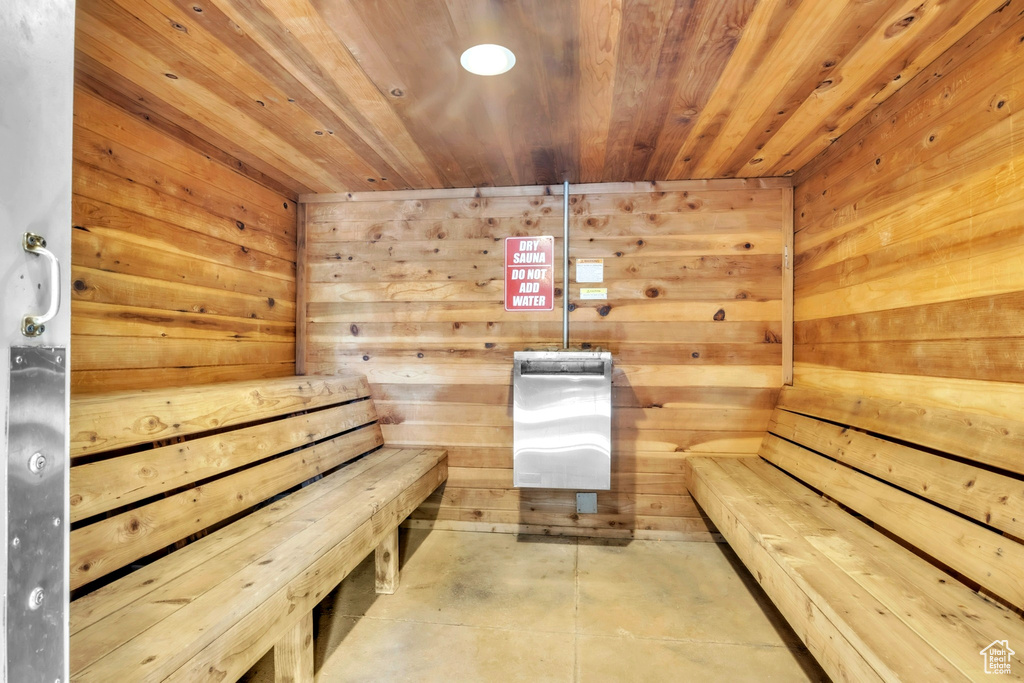 Relaxing sauna / steam room with wood ceiling, wooden walls, and concrete flooring