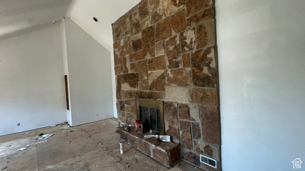 Unfurnished living room with vaulted ceiling and a stone fireplace