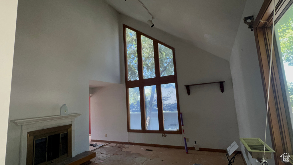 Unfurnished living room with a glass covered fireplace and a towering ceiling