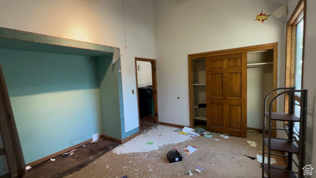 Unfurnished bedroom featuring a high ceiling and baseboards